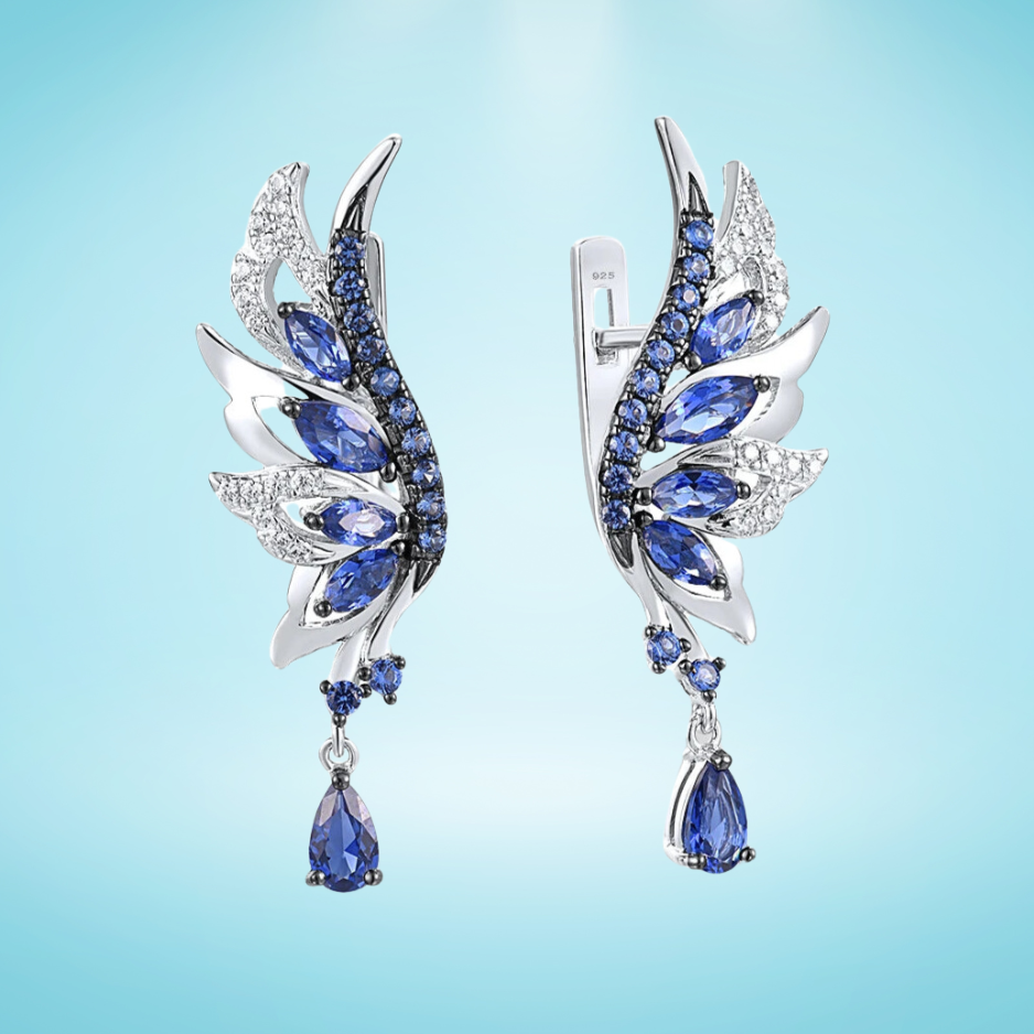 Silver earrings shaped like angel wings, set with layered blue and white stones and teardrop dangles