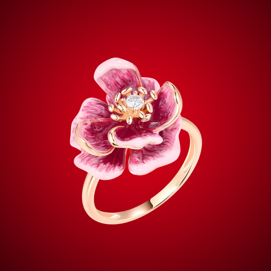 Pink and burgundy enamel flower ring with a central clear gemstone on a gold-tone band.