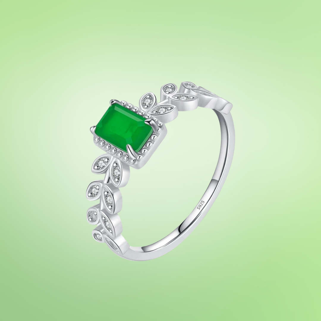 Rectangular green gemstone ring with delicate leaf-inspired silver accents and small clear stones.