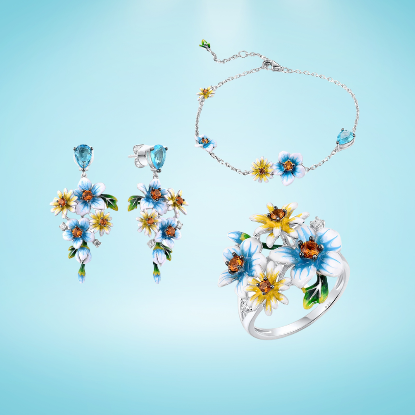 Floral jewelry set with enamelled white, blue, and yellow blossoms, accented by orange and blue gemstones