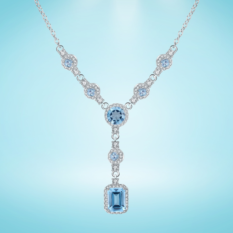 Silver necklace with round and emerald-cut light blue stones and halo settings