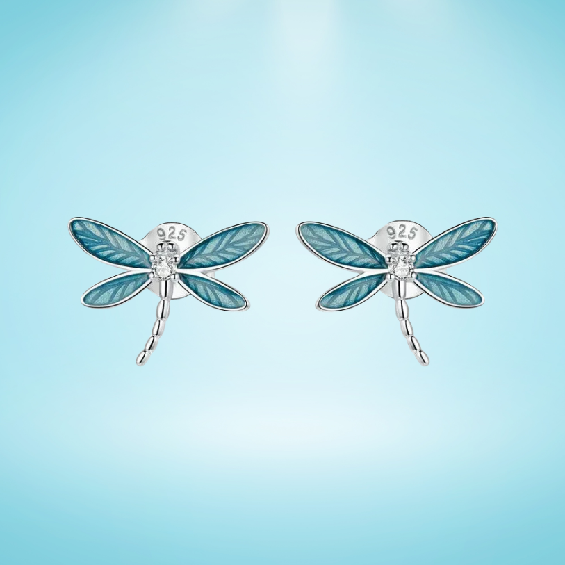 Silver dragonfly stud earrings with translucent blue enamel wings and a tiny clear gemstone on the body