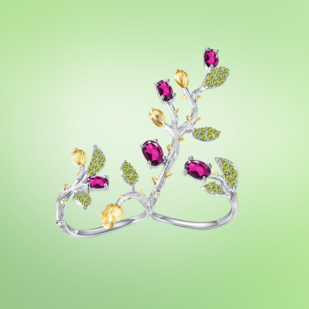 Twin silver rings with ruby pink stones, yellow buds, and light green leaf accents