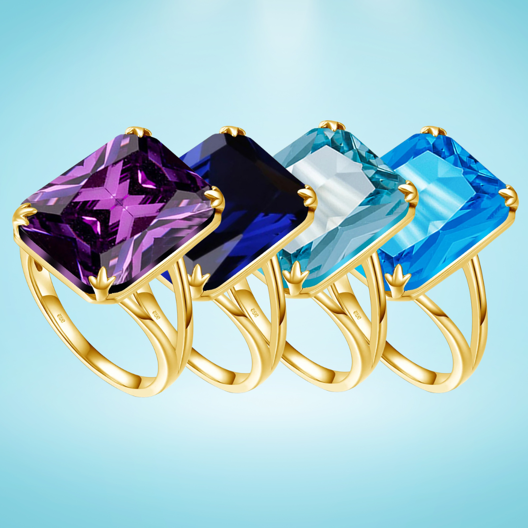 Gold rings with large square-cut gemstones in amethyst purple, deep sapphire blue, icy aquamarine, and bright sky blue on a light blue background