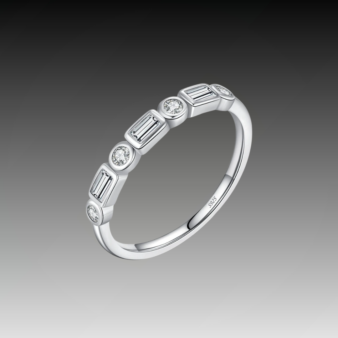 Silver ring featuring alternating round and baguette-cut white stones in a half-band setting.