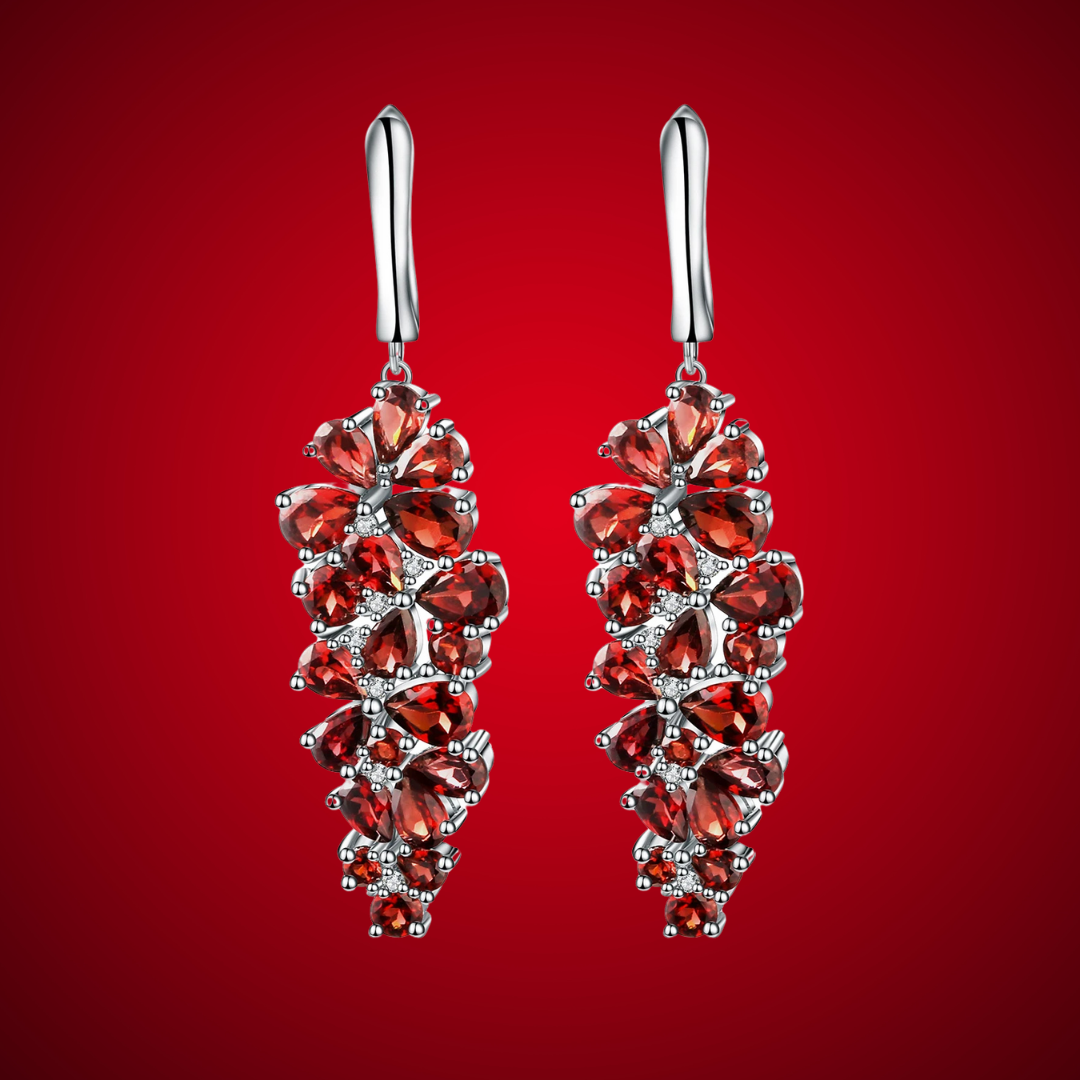 Dangling silver earrings adorned with clusters of deep red gemstones in grape-like floral formations.