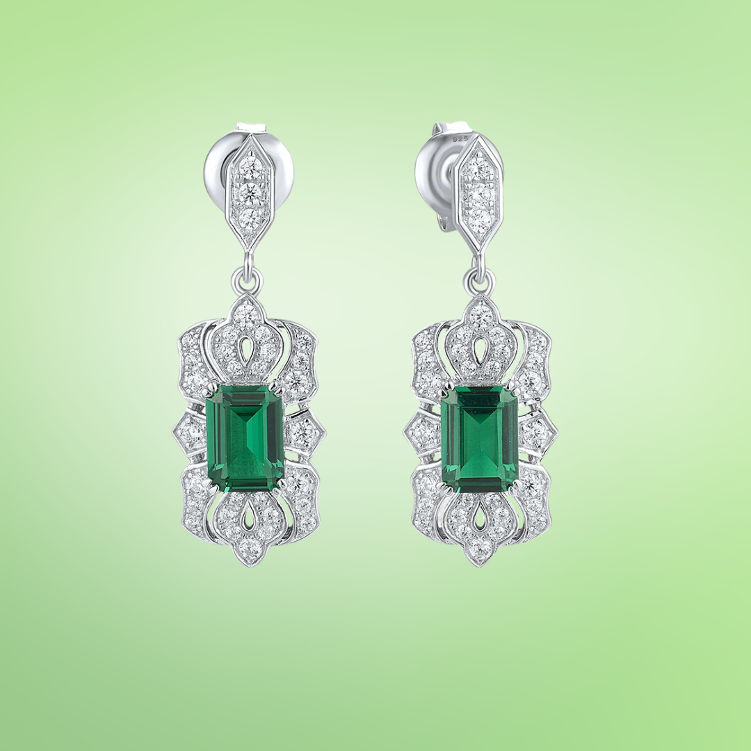 Art Deco-inspired drop earrings with green emerald-cut stones and intricate pavé detailing