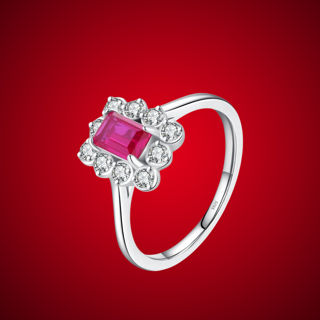 Silver ring with rectangular ruby-pink gemstone surrounded by clear stones in a floral cluster