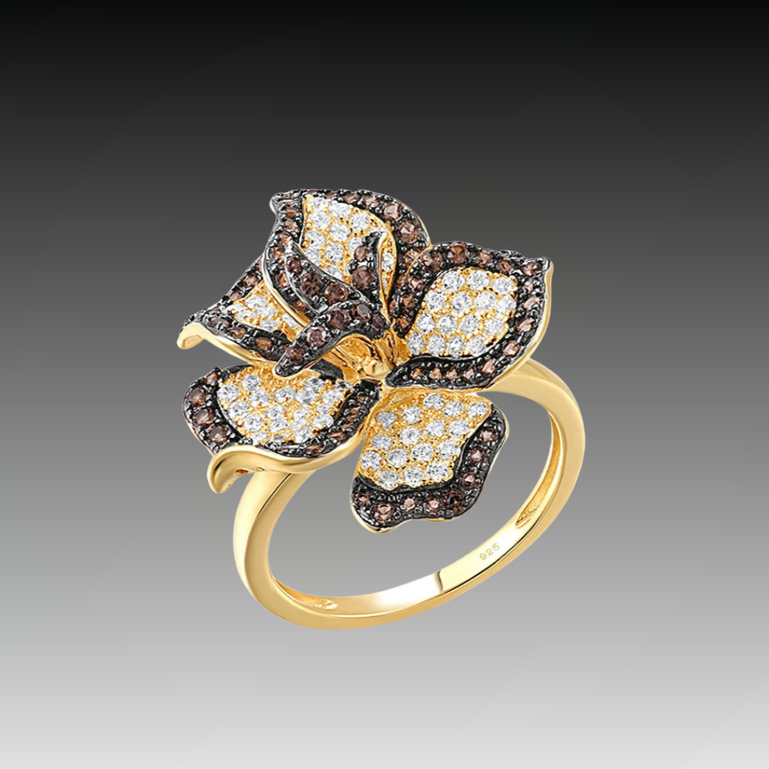 Gold ring with a large, sparkling flower design featuring white and brown stones on each petal.