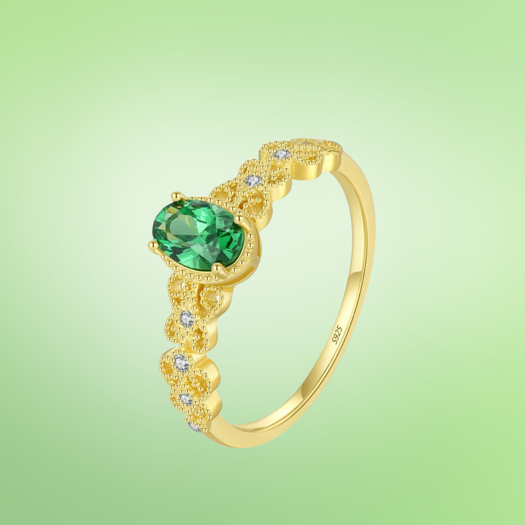 Gold-plated silver ring with a green oval gemstone and delicate diamond-accented detailing.