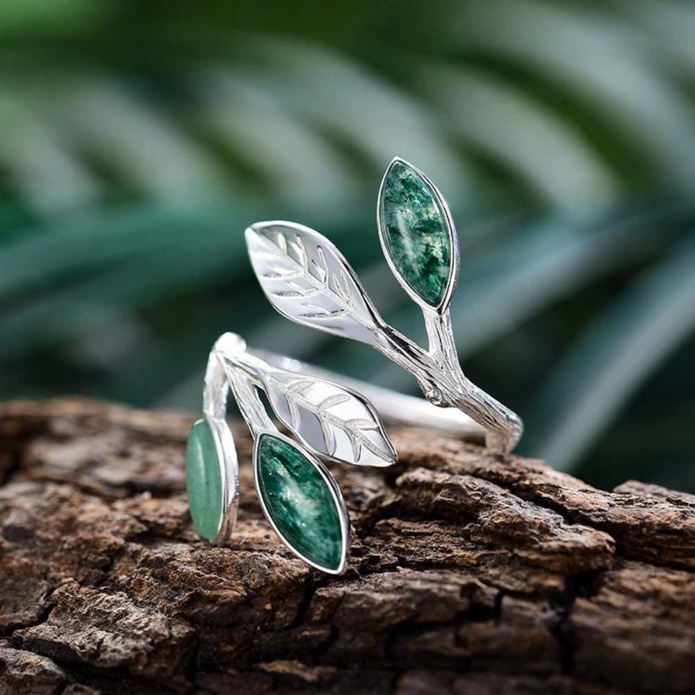 Adjustable silver ring featuring green marbled leaf accents in an open branch design.