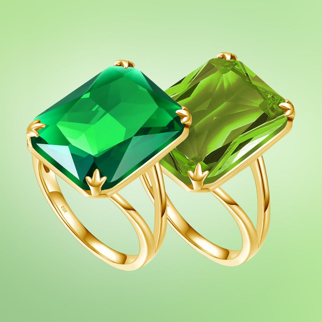 Two bold green gemstone rings with gold bands, one deep emerald green and the other a lighter peridot tone
