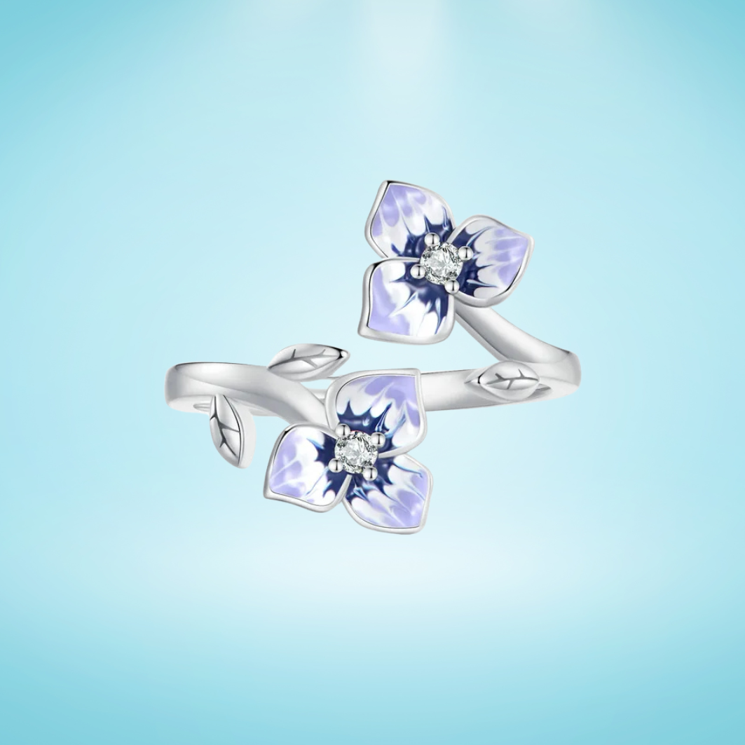 Sterling silver wrap ring featuring two delicate purple and white enamel flowers with clear center stones and leaf details.