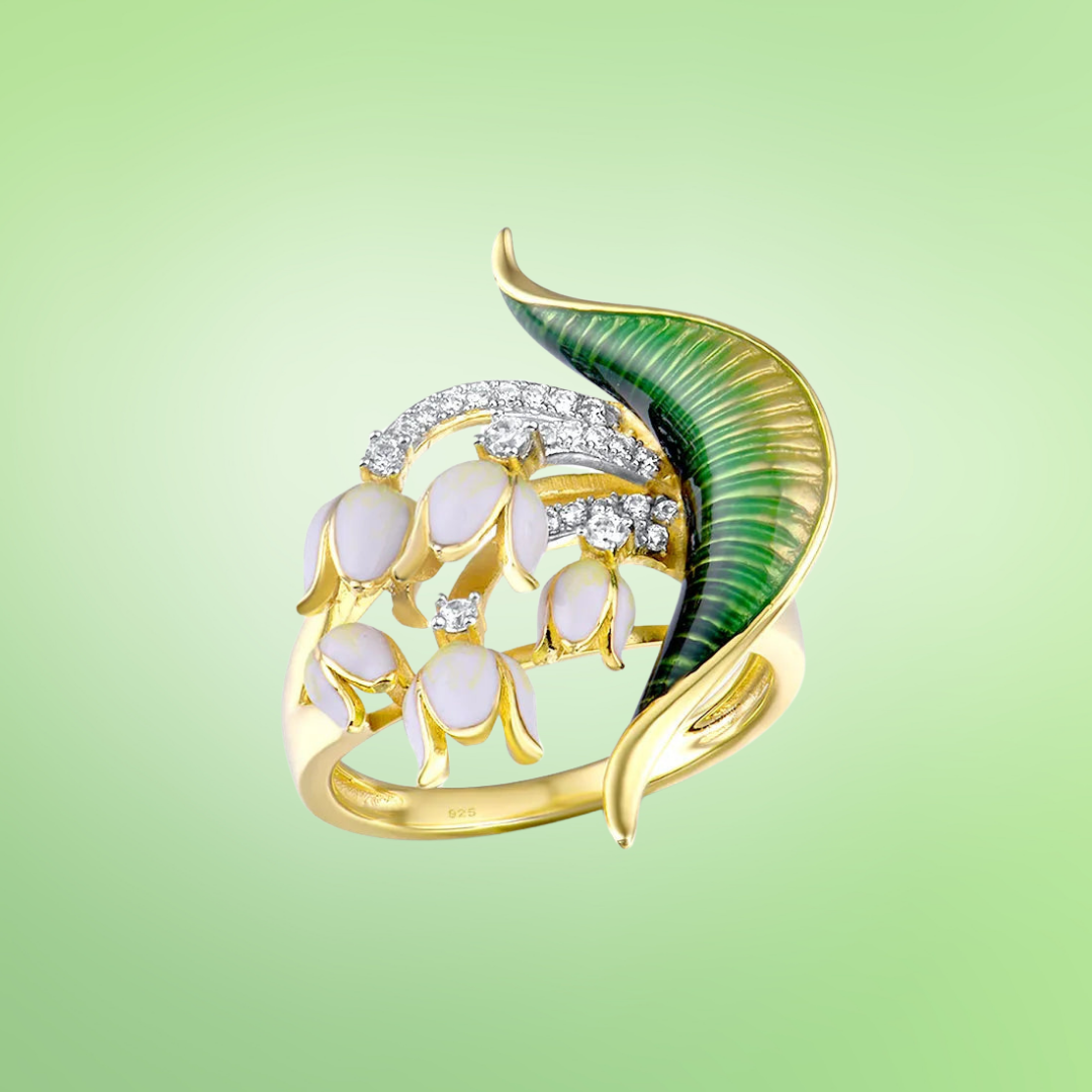 Gold ring featuring a sculpted green enamel leaf, curved pavé-set arcs, and clusters of small pink flower buds