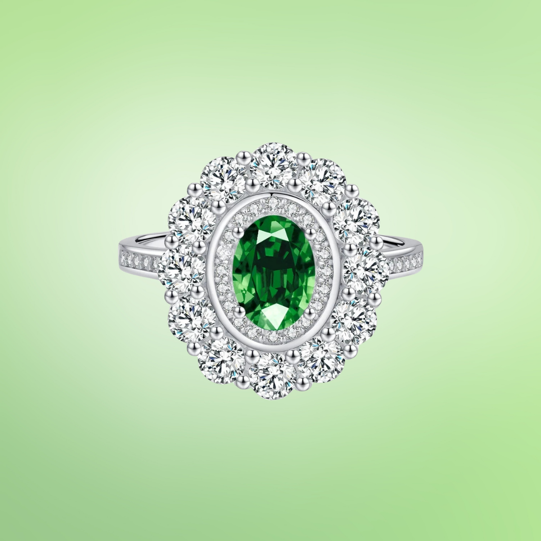 Oval green gemstone ring with a double halo of white zirconia set in polished silver.