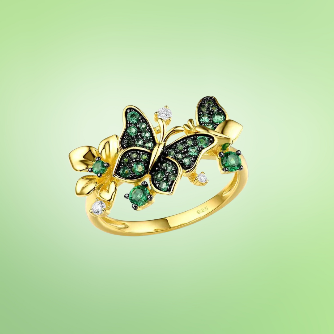 Gold butterfly ring adorned with green crystals and delicate flower accents