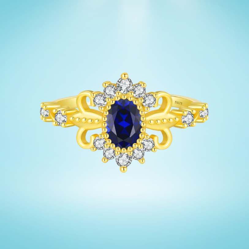 Vintage-style gold ring with deep blue oval center stone surrounded by clear accent stones