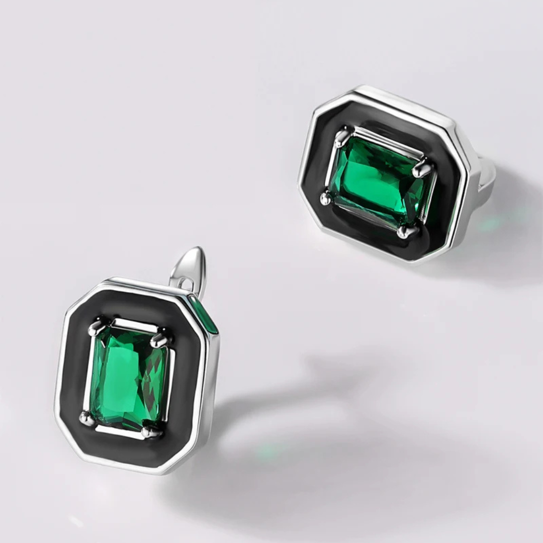 Silver earrings with black enamel octagonal frames and green emerald-cut stones at the center