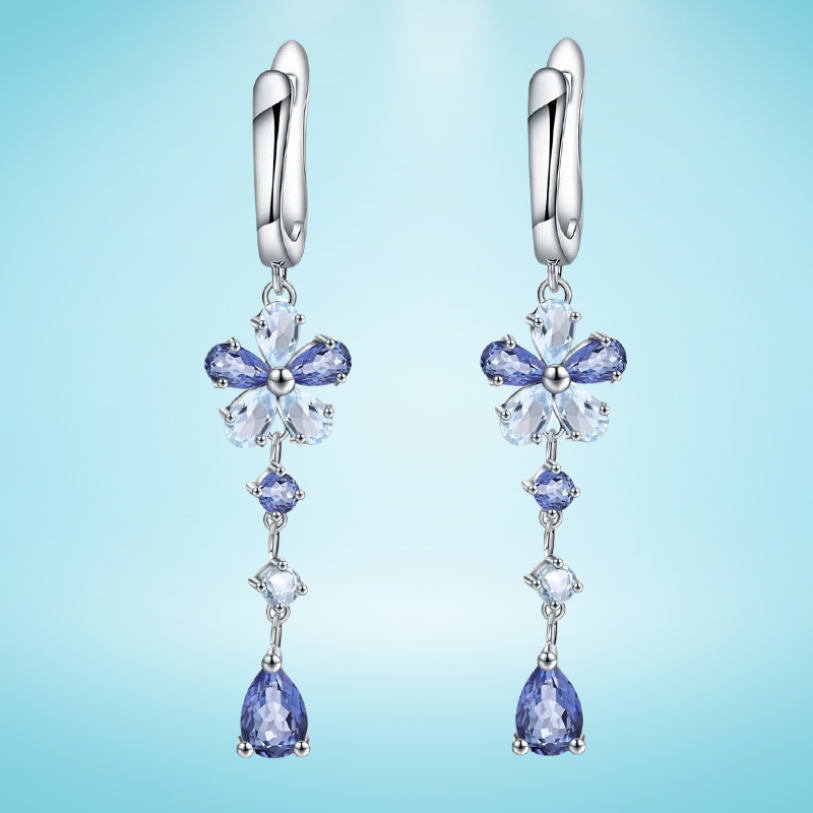 Drop earrings featuring floral blue gemstone clusters and pear-cut drops on a silver setting