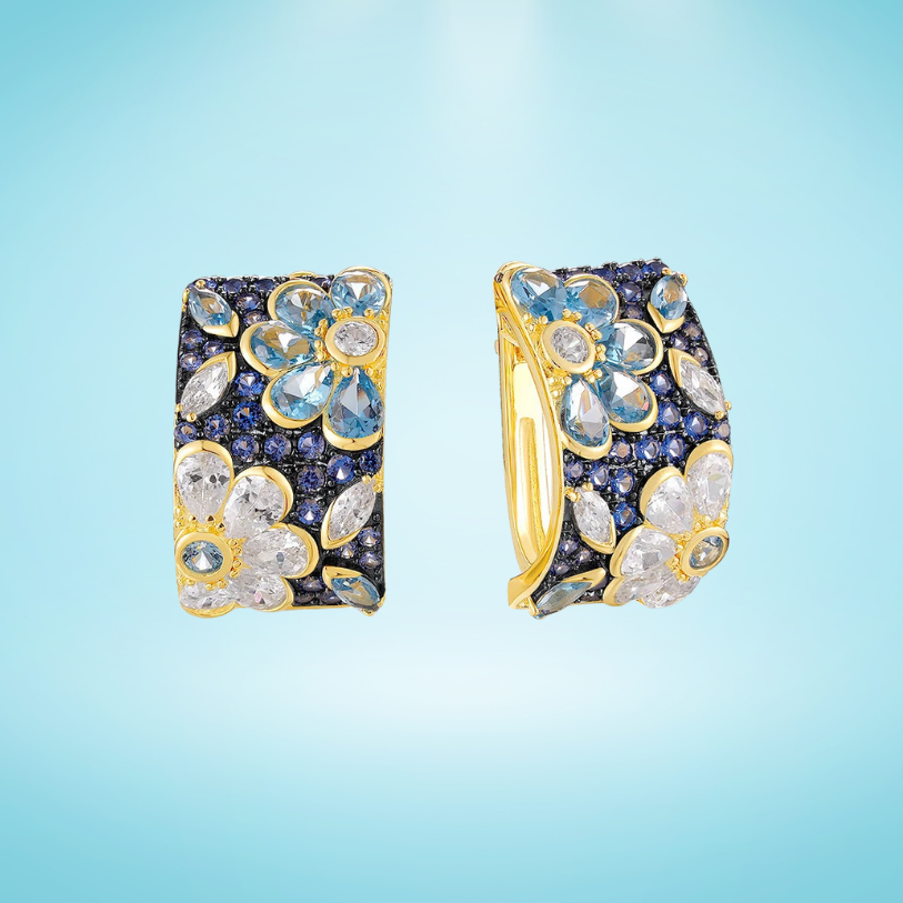 Gold-plated hoop earrings with floral gemstone clusters in blue and white on a dark pavé background