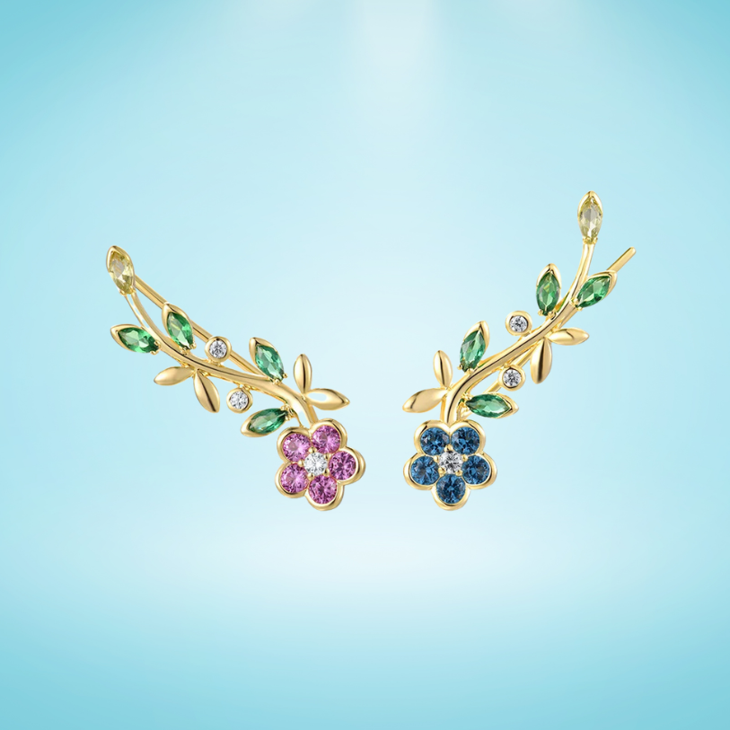 Asymmetrical gold earrings with colorful crystal flowers and green gemstone vines