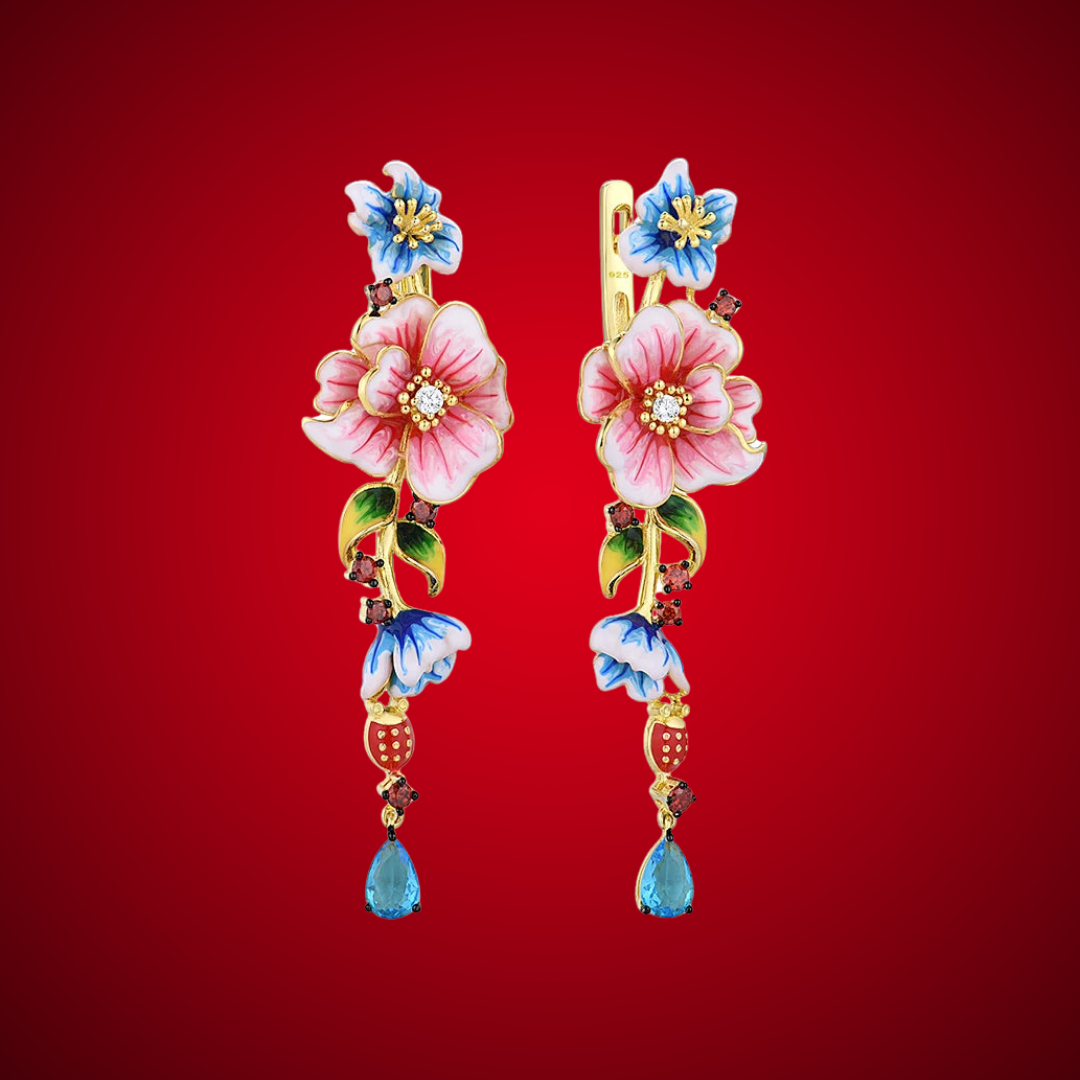 Gold drop earrings featuring pink and blue enamel flowers, green leaves, and teardrop blue gemstone accents.