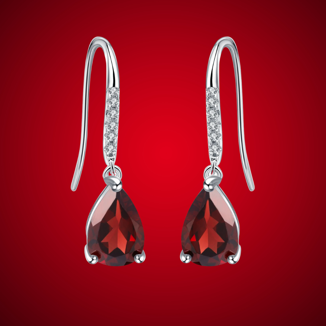 Silver hook earrings with deep red teardrop gemstones and pavé-set clear stones on the upper hooks.