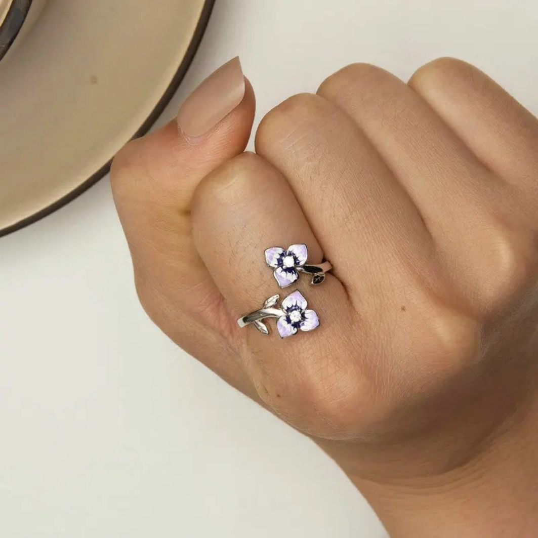 Sterling silver wrap ring featuring two delicate purple and white enamel flowers with clear center stones and leaf details.