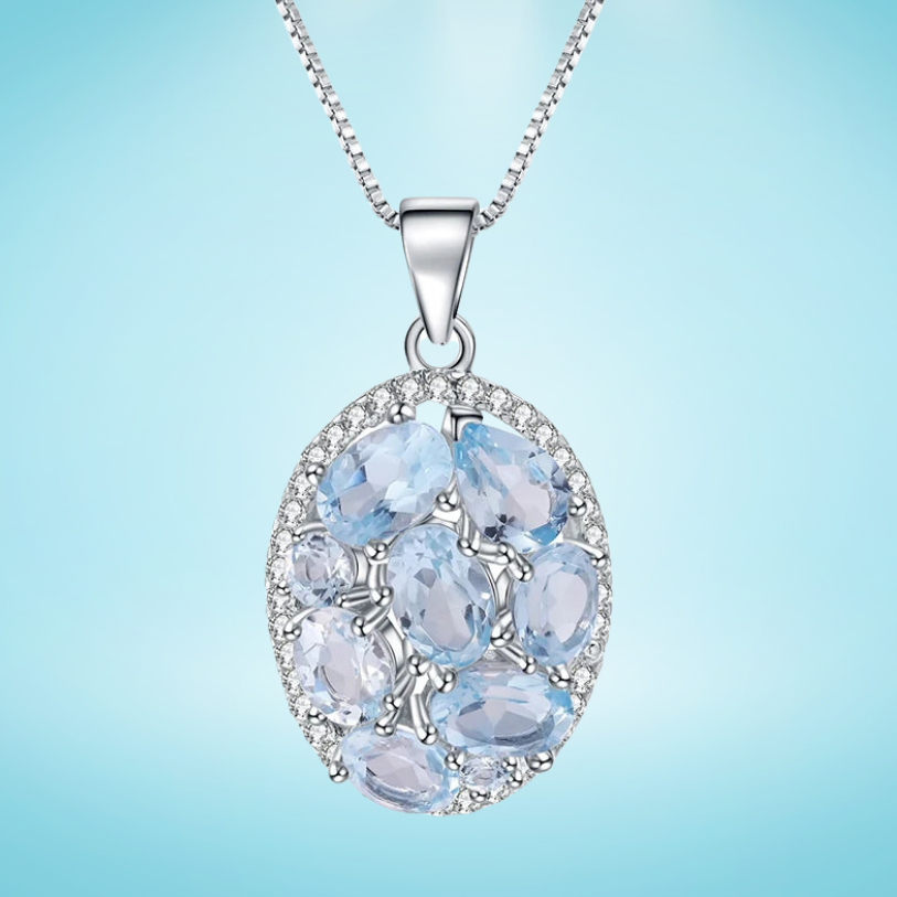Oval silver pendant with light blue gemstones and surrounding crystal accents