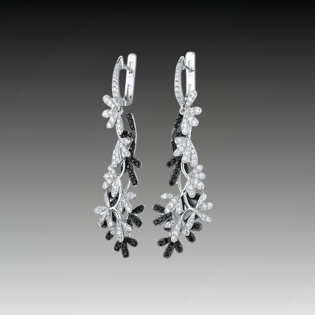 Long silver earrings with interwoven black and white gemstone-studded olive leaf designs.