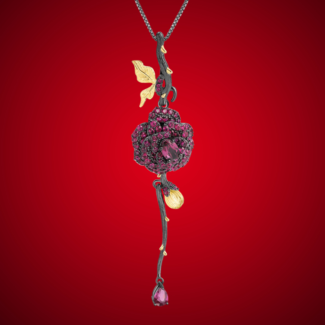 Pendant necklace with a dark rose-shaped bloom in ruby stones, accented by golden leaves and a delicate drop, from the Rossa Collection.