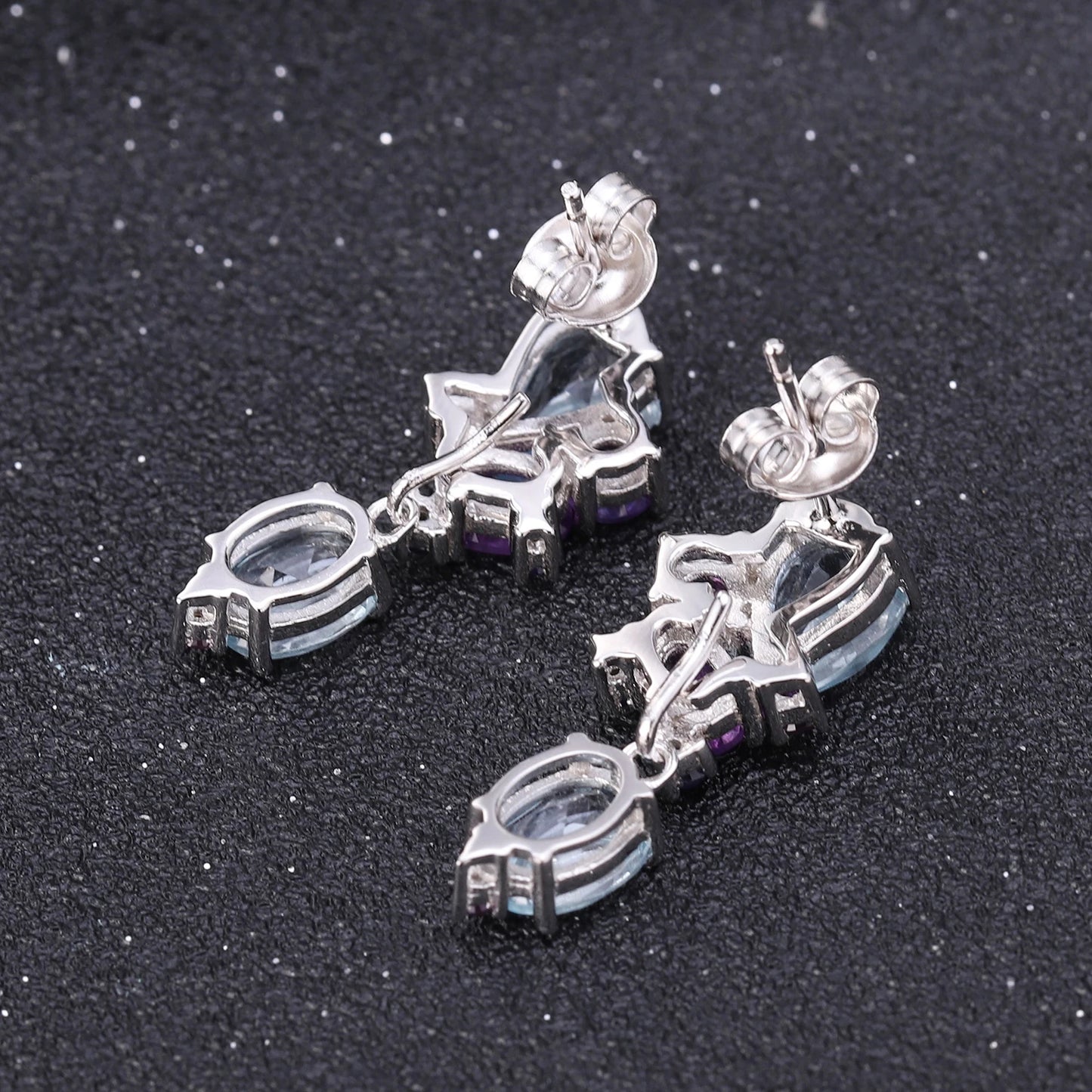 Drop earrings with pear-cut and oval blue gemstones arranged in an asymmetrical floral-inspired design