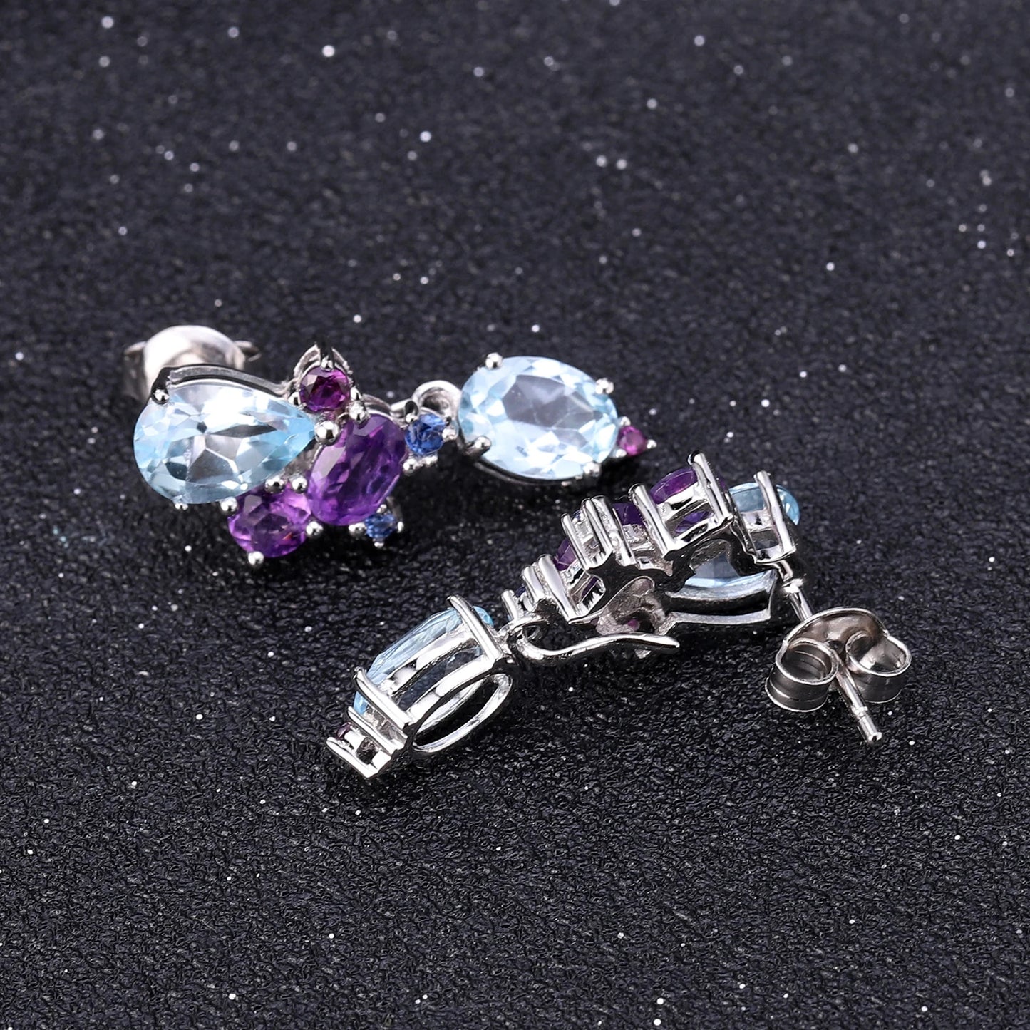 Drop earrings with pear-cut and oval blue gemstones arranged in an asymmetrical floral-inspired design