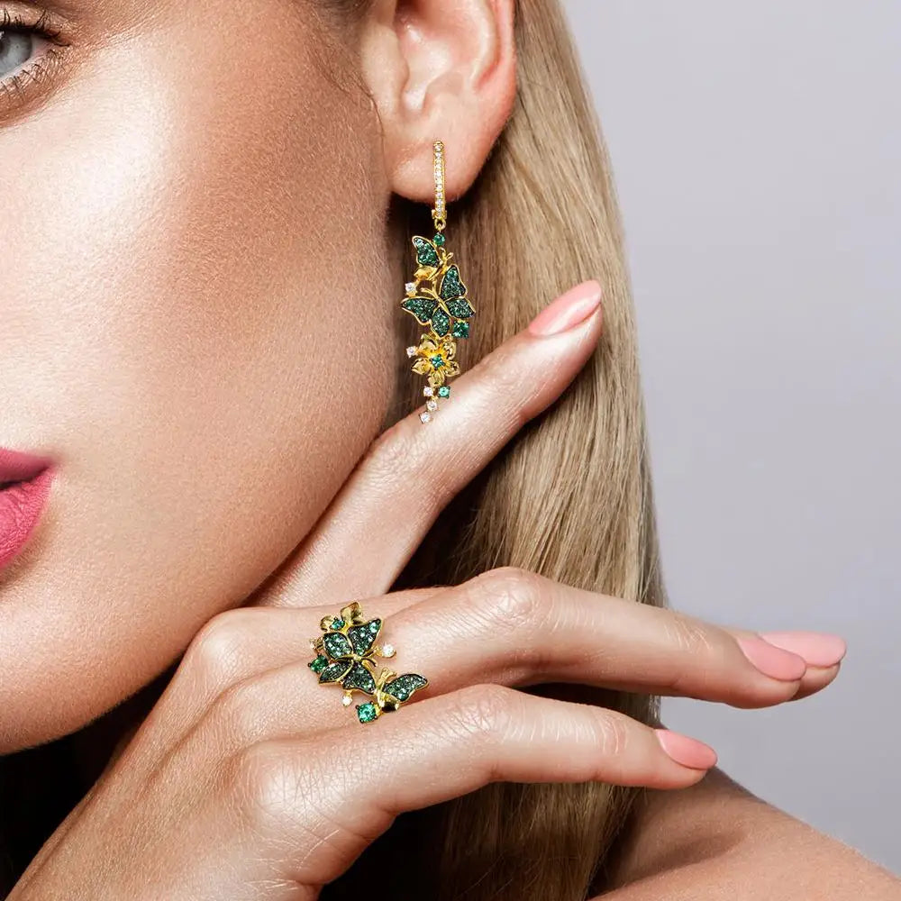 Gold butterfly ring adorned with green crystals and delicate flower accents