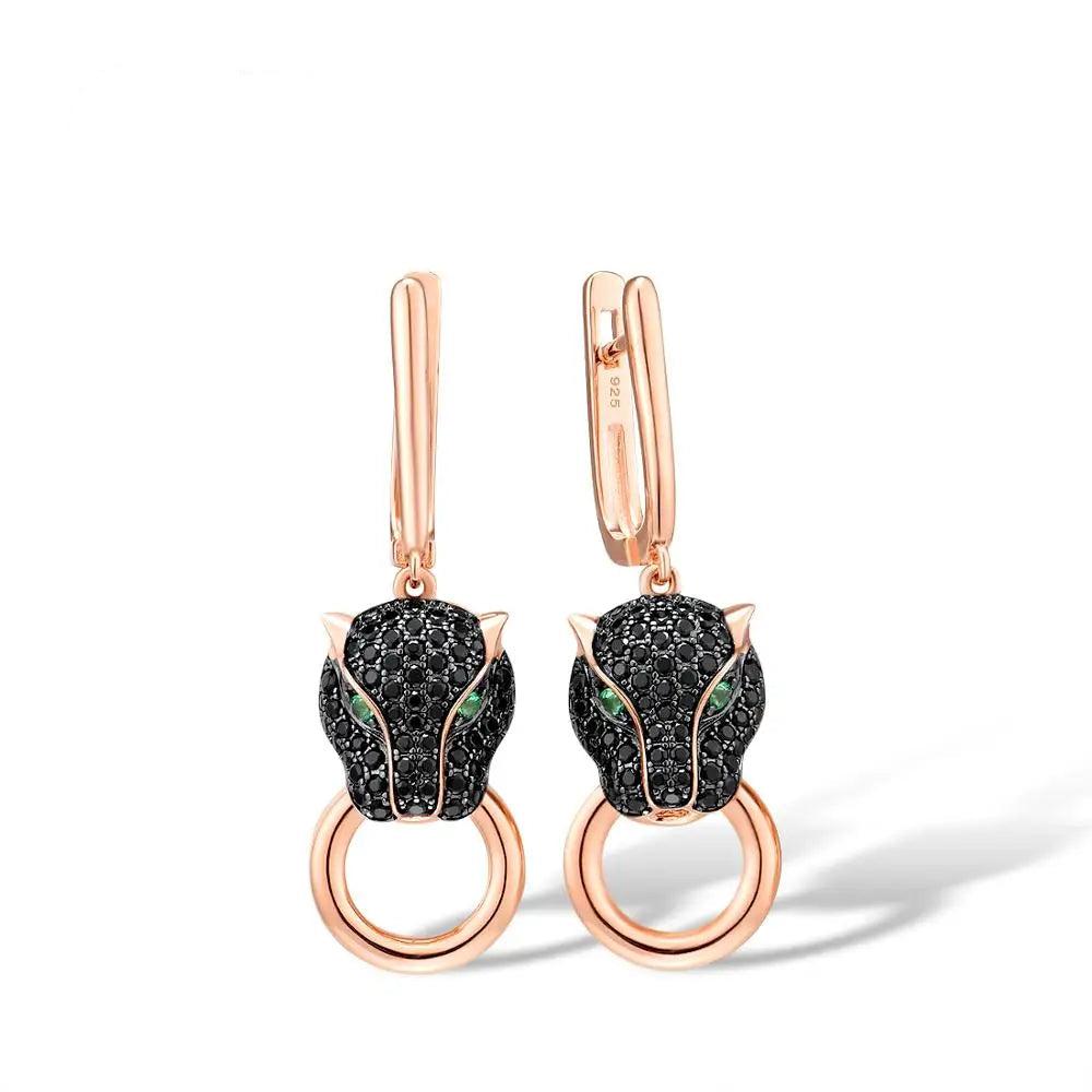 Rose gold earrings featuring black panther heads with green gemstone eyes and ring details.