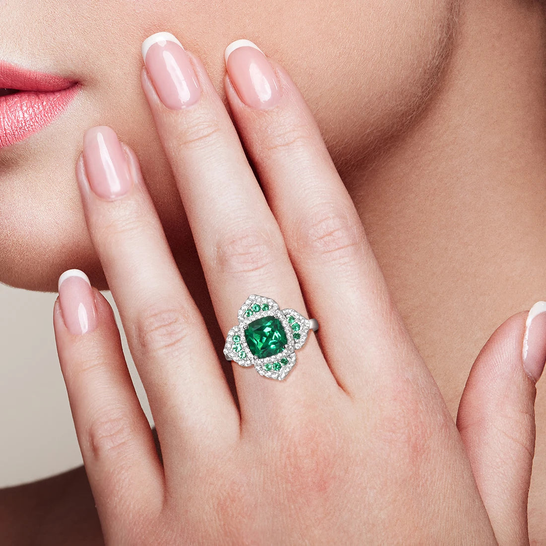 Silver ring with a large cushion-cut green center stone, surrounded by pavé-set crystals in a layered floral-inspired setting