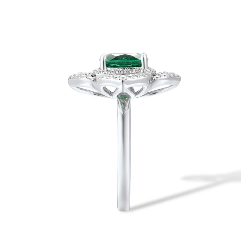 Silver ring with a large cushion-cut green center stone, surrounded by pavé-set crystals in a layered floral-inspired setting