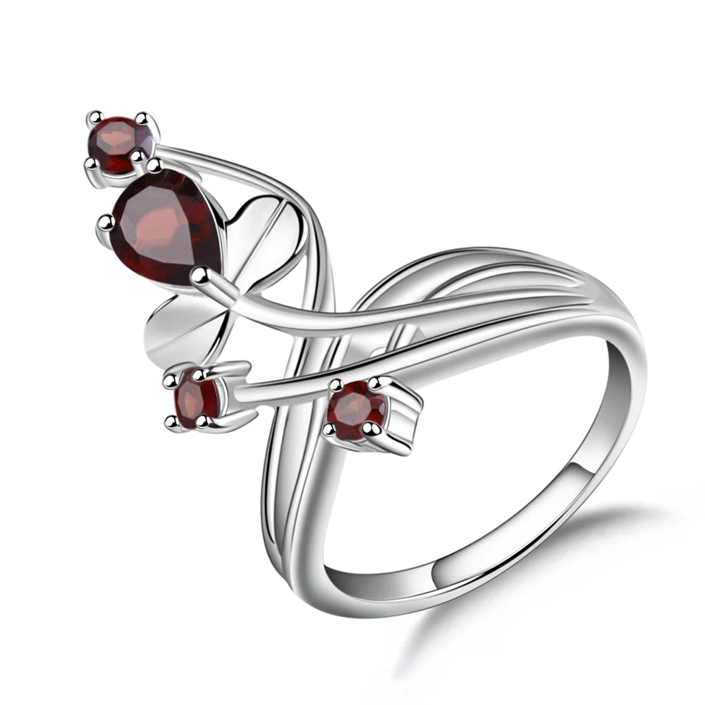Silver ring with a curved, nature-inspired design, set with deep red round and pear-shaped stones.