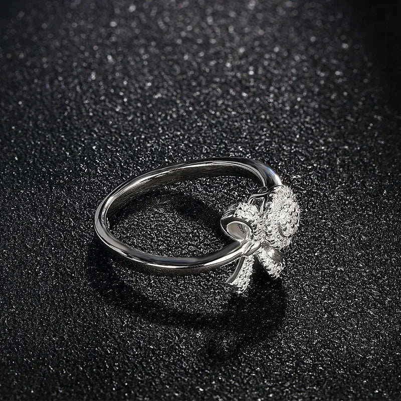 Delicate silver ring featuring a sparkling bow and circular cluster of clear stones in a graceful, feminine design.