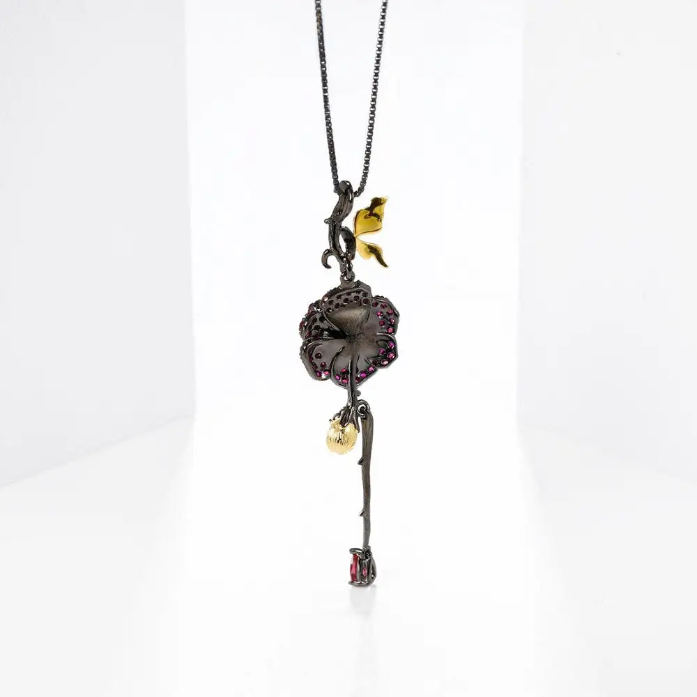 Pendant necklace with a dark rose-shaped bloom in ruby stones, accented by golden leaves and a delicate drop, from the Rossa Collection.