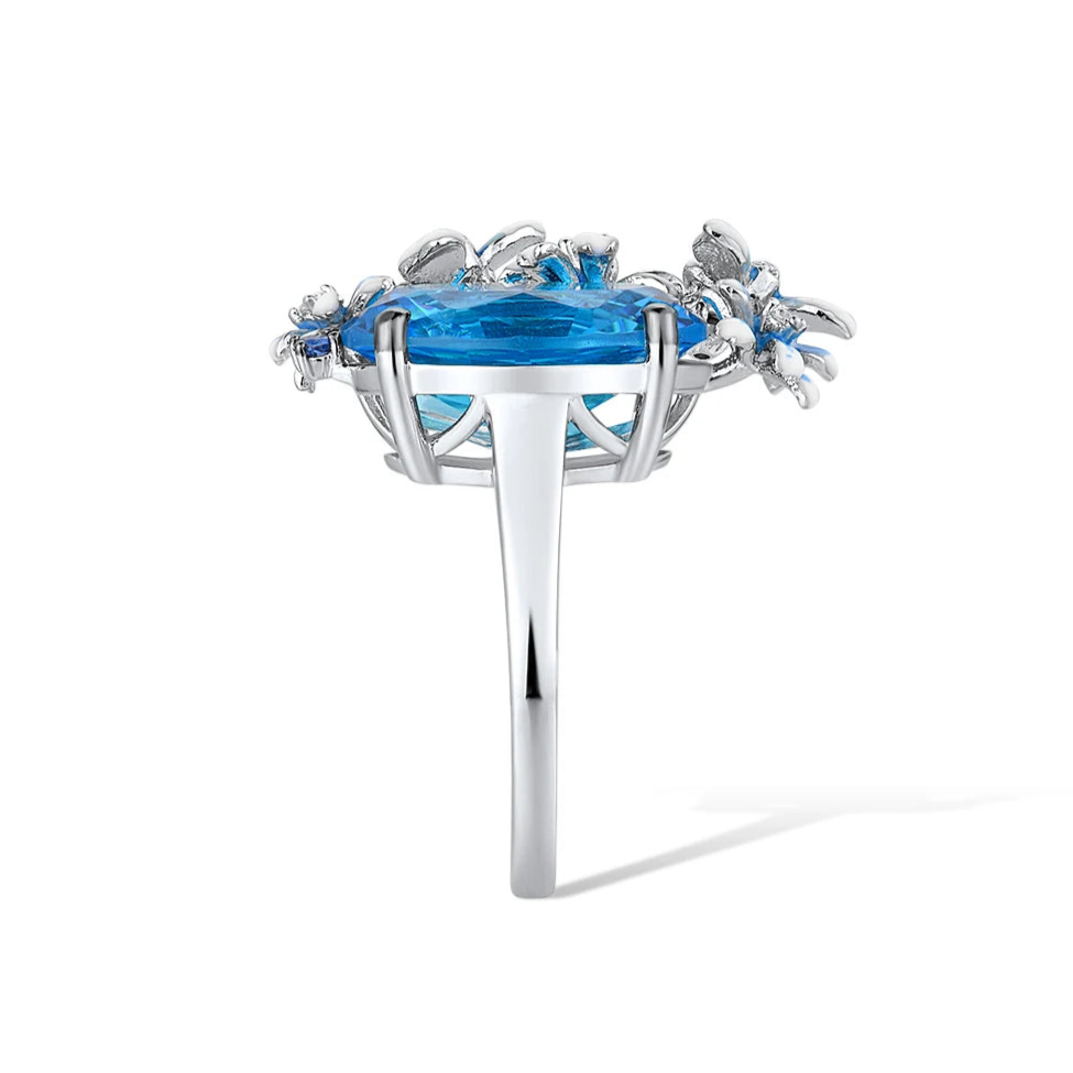 Silver ring with a large blue gemstone surrounded by butterflies and enamel flowers in soft blue tones