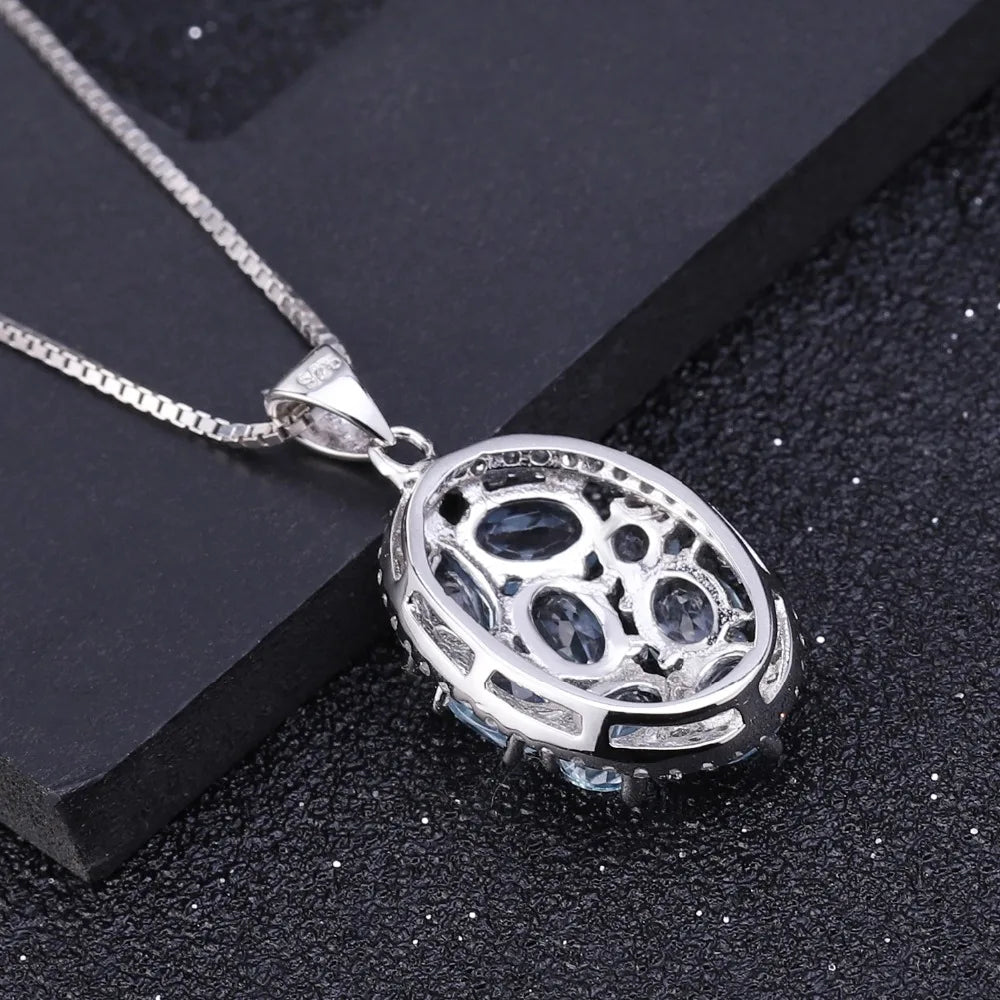 Oval silver pendant with light blue gemstones and surrounding crystal accents