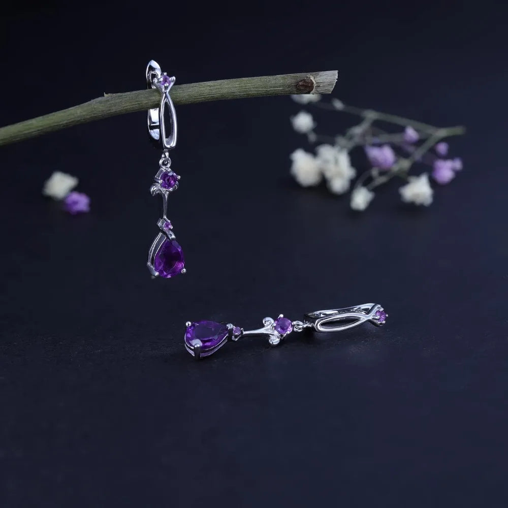 Dangling silver earrings with purple teardrop stones and delicate swirl detailing