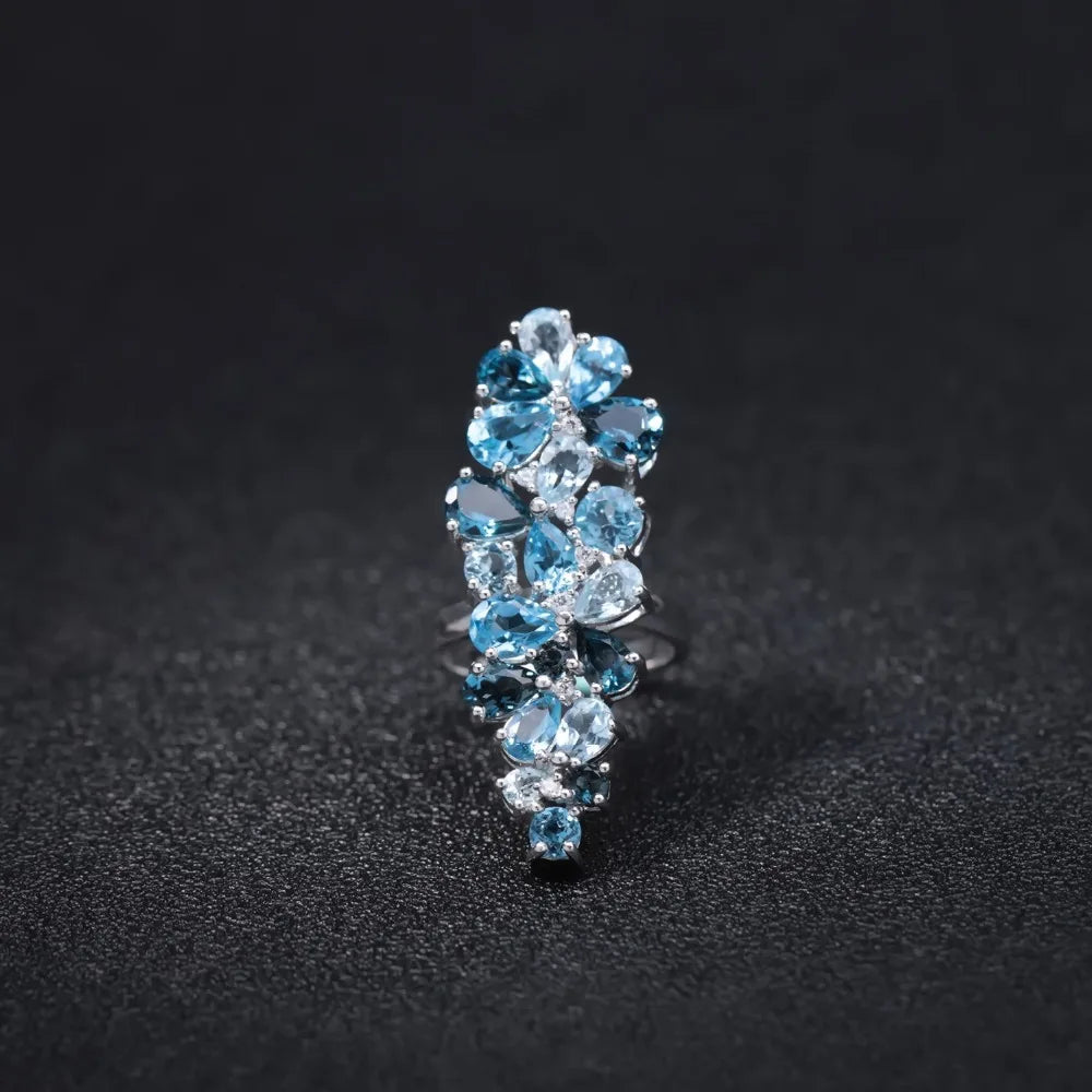 Sterling silver ring adorned with clusters of pear-cut and round-cut blue topaz gemstones in varying shades.