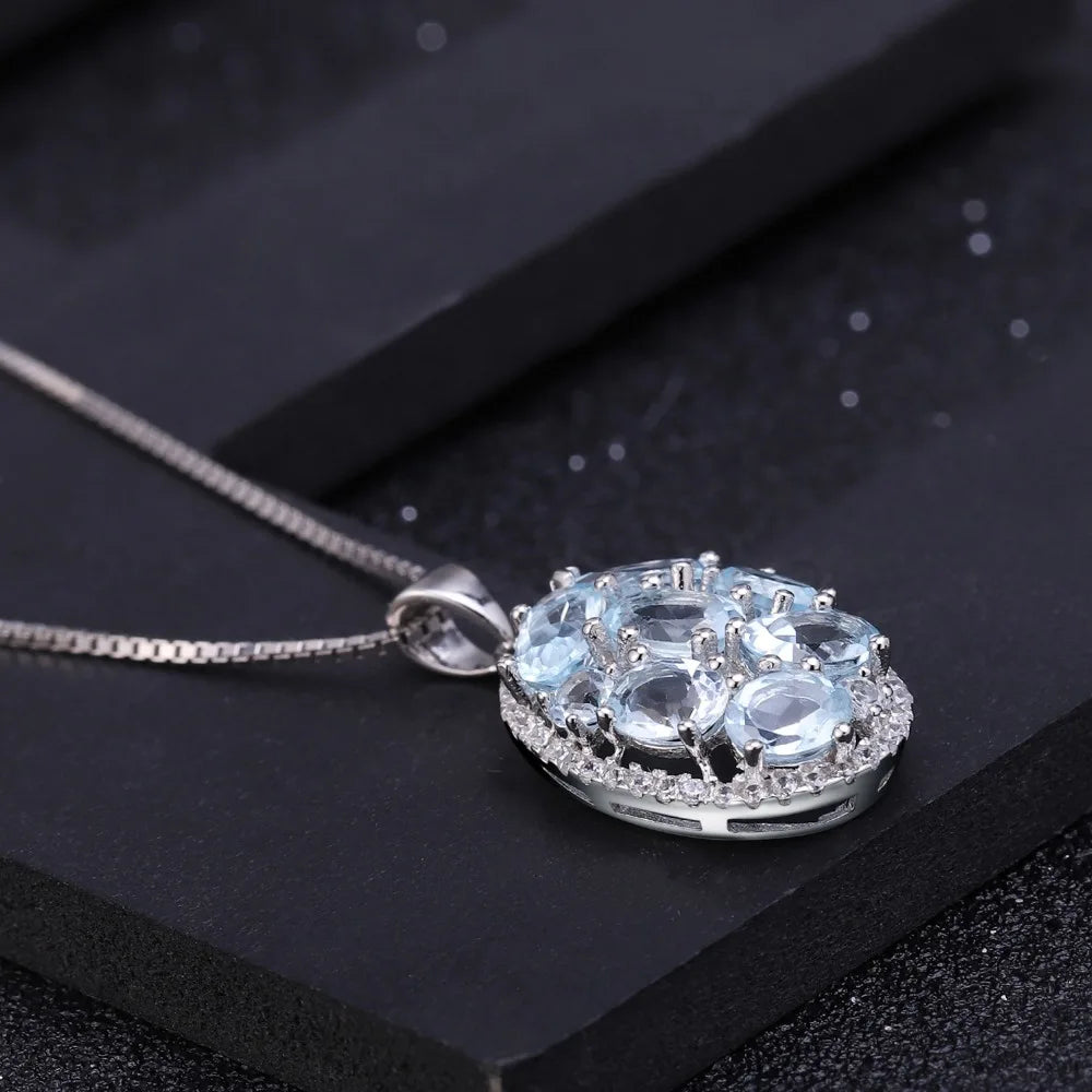 Oval silver pendant with light blue gemstones and surrounding crystal accents