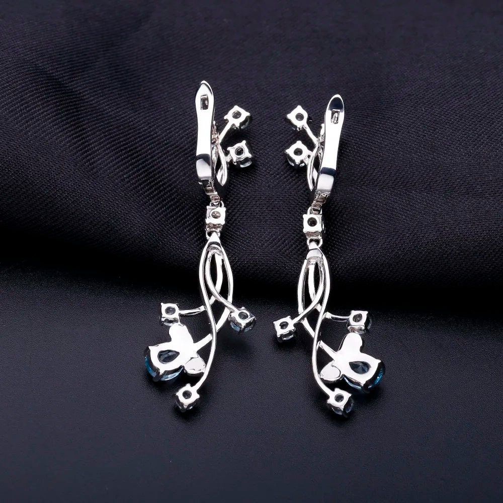 Sterling silver drop earrings with curved lines and scattered light blue gemstones resembling delicate flower petals