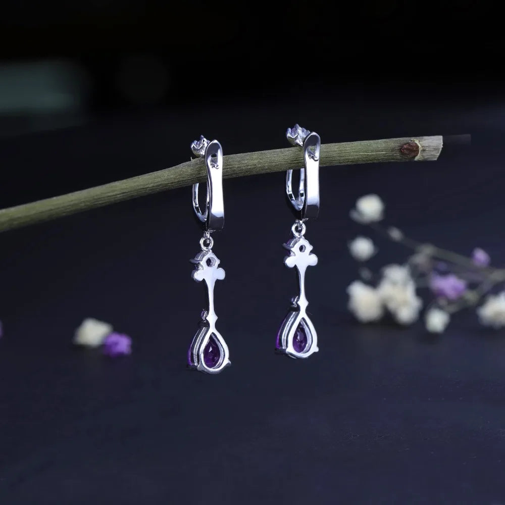 Dangling silver earrings with purple teardrop stones and delicate swirl detailing