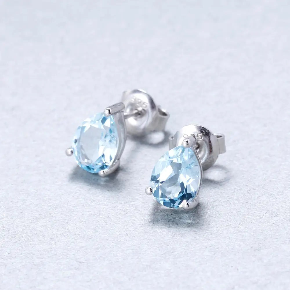 Sterling silver stud earrings with pear-shaped blue topaz gemstones in a three-prong setting