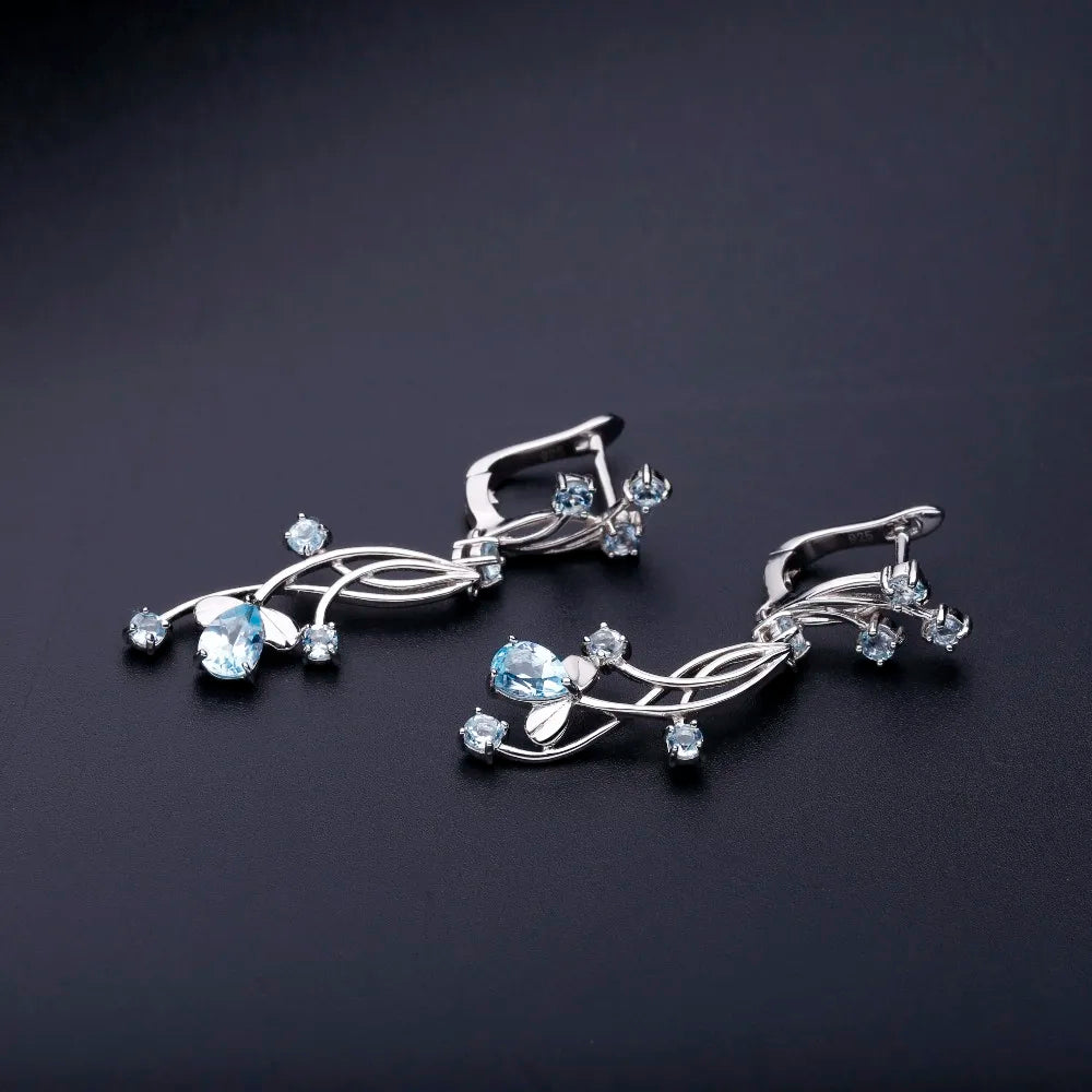 Sterling silver drop earrings with curved lines and scattered light blue gemstones resembling delicate flower petals