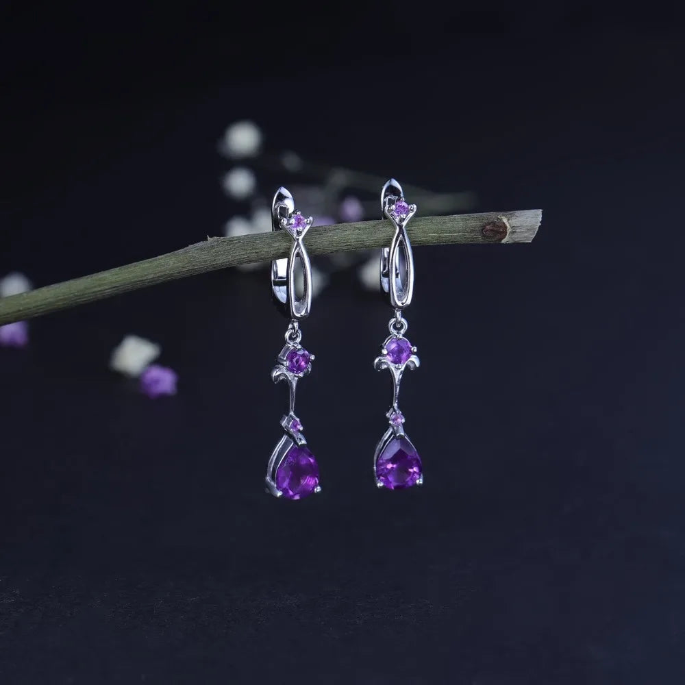 Dangling silver earrings with purple teardrop stones and delicate swirl detailing